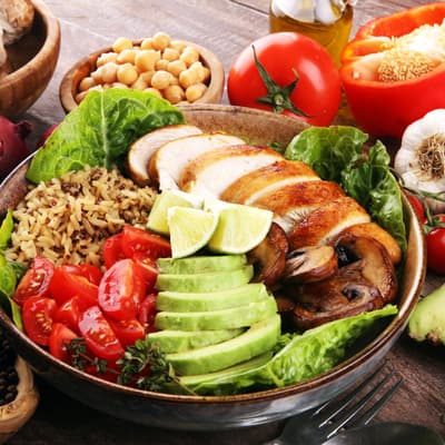 Healthy salad bowl with quinoa, tomatoes, chicken, avocado, lime and mixed greens, lettuce